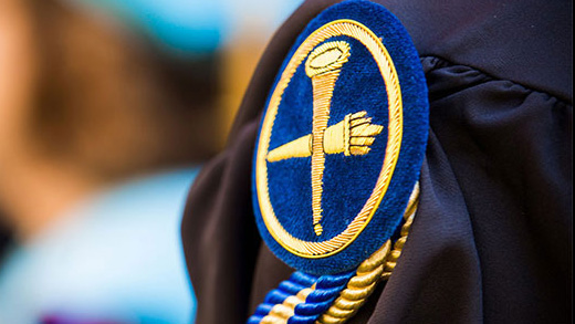 A closeup of an Emory shield on graduation regalia