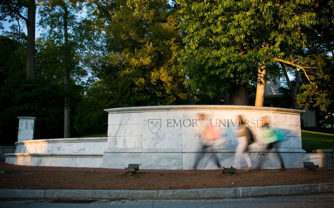 Emory University's front gates with students walking by in a blur of motion