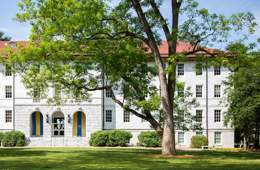 white and gray granite building with red tile roof and emory banners hanging by the door