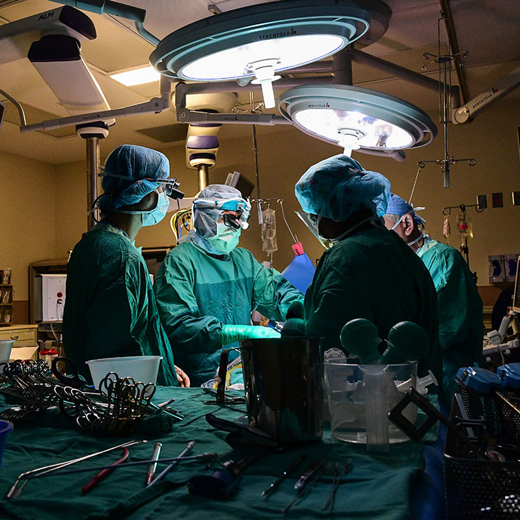 in an operating room, medical personnel work on a patient