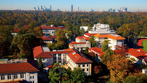 aerial view of campus with red tile roofs, city skyline in distance